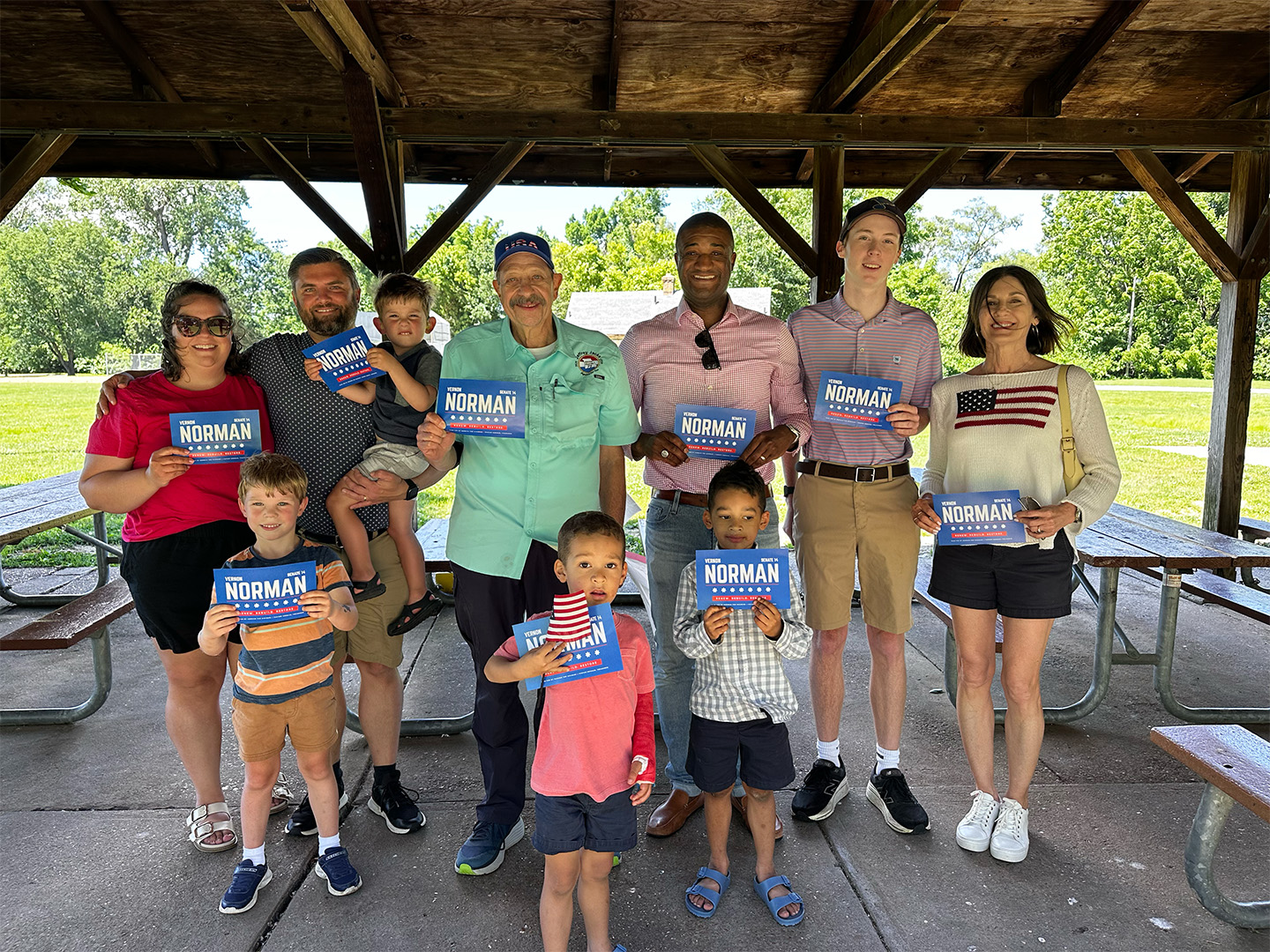 Vernon Norman standing with constituents of various ages, from children to adults, holding signs that read Vernon Norman Senate 14