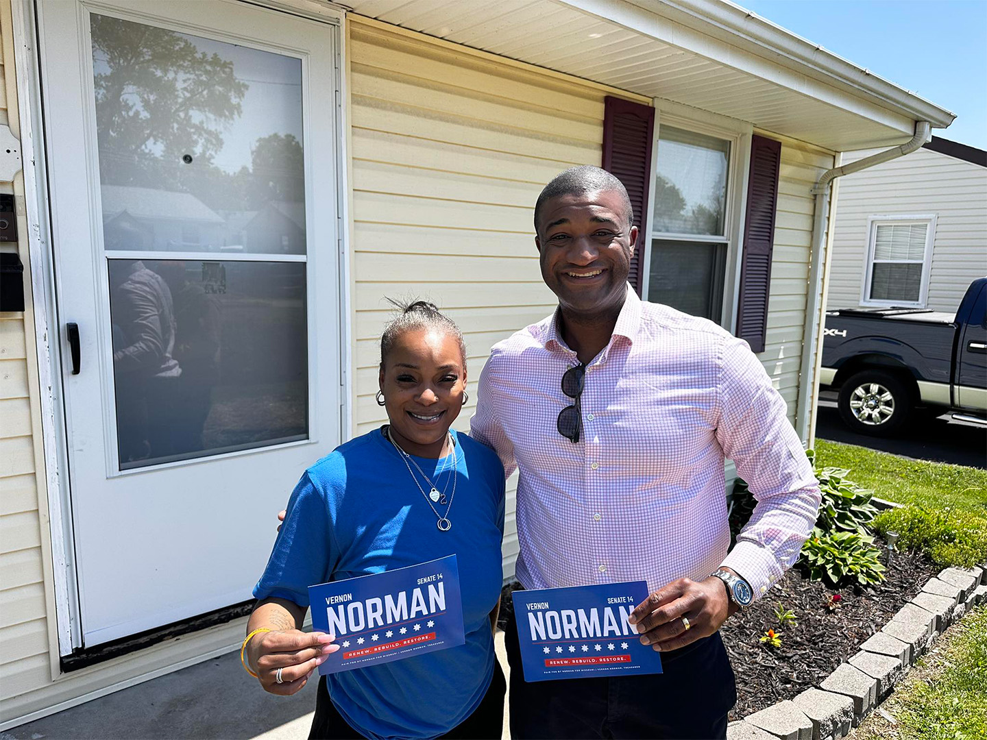 Vernon Norman smiling with a female constituent holding signs that read Vernon Norman 